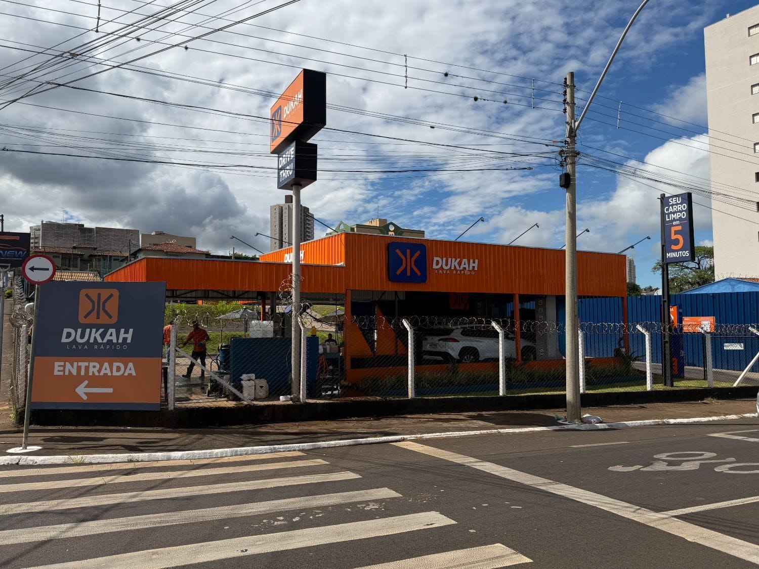 Vista da unidade Dukah da rua com poste DRIVE THRU e placa Entrada